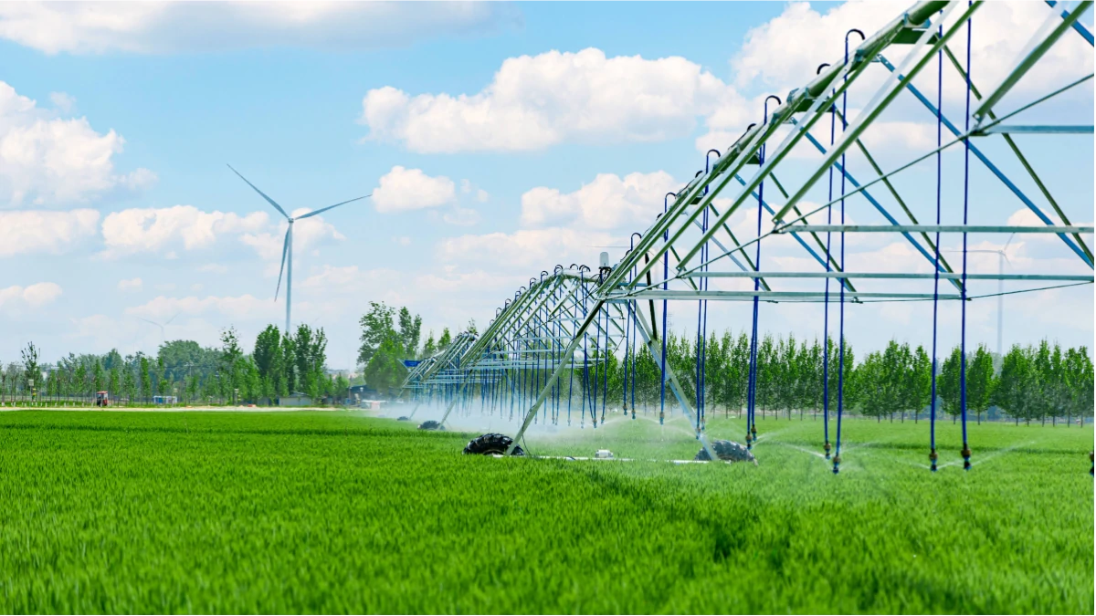 Automated agricultural sprinkler system irrigating a green field, powered by a high-capacity 6 inch submersible well pump.