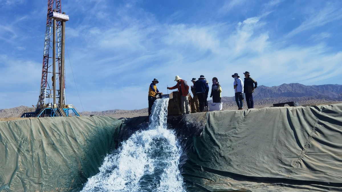 A large-scale drilling rig operating in a desert mountain region, discharging a heavy flow of water into a lined reservoir—a classic application for a high-capacity 6 inch Submersible pump.