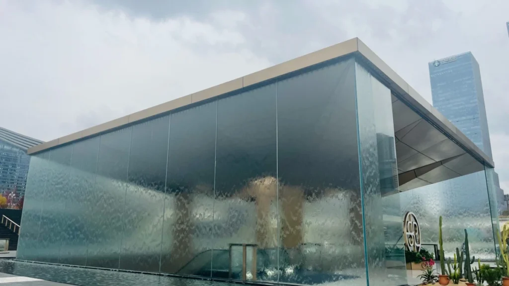 An elegant glass water wall feature in a luxury hospitality setting, showcasing a seamless cascading effect powered by a high-performance 4sp8 fountain pump.