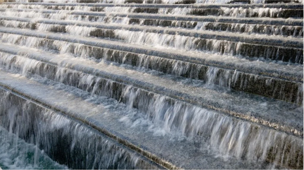 A large stone water feature with cascading tiered waterfalls driven by a high-capacity 4sp3 fountain pump.